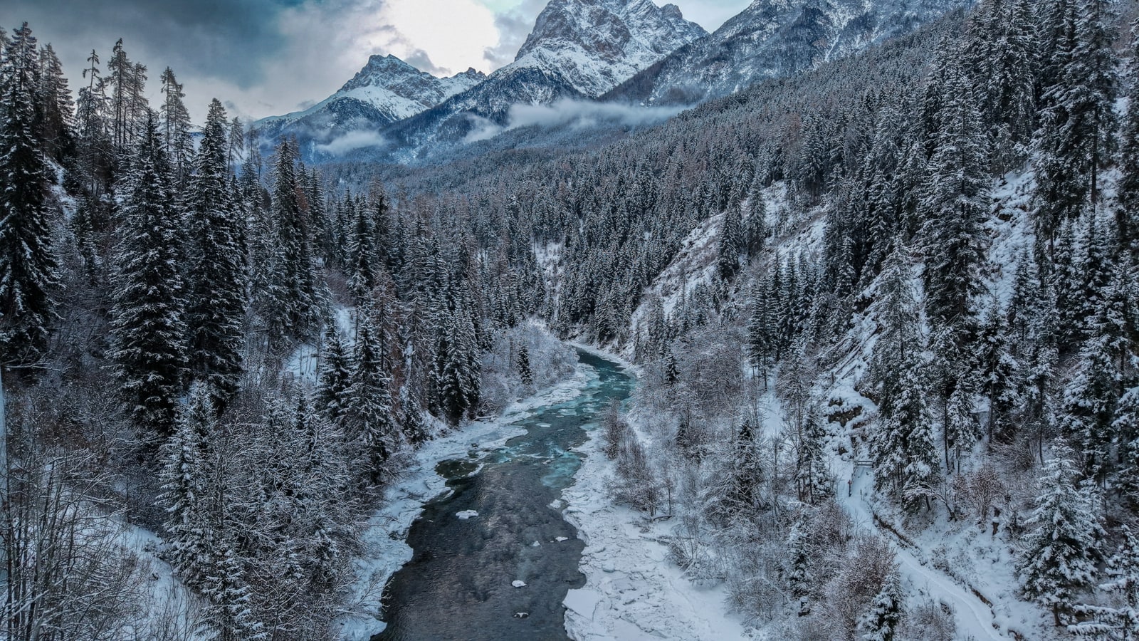 Winter wonderland aerial view of snow-blanketed Swiss village nestled in alpine valley with crystalline white landscape